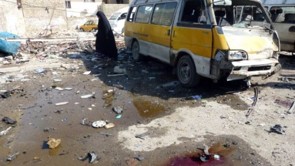 An Iraqi woman walks across the debris following an explosion at a bus center on October 27, 2013, in the the Mashtal district of the capital Baghdad, as eight car bombs exploded in Shiite-majority areas of Baghdad province. (AFP)