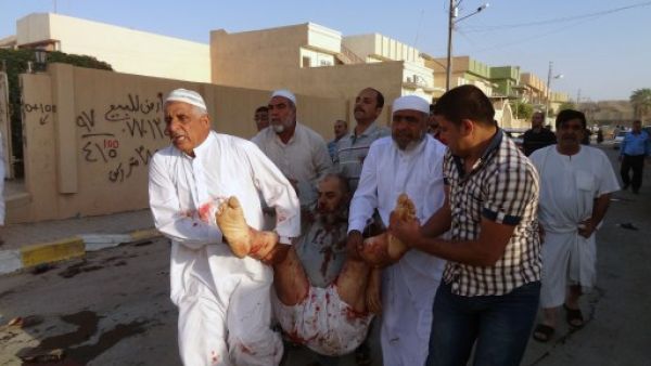 Iraqis carry a wounded man at the scene of a car bomb attack after it exploded as worshippers left a Sunni mosque following prayers marking the start of the Eid Al Adha Muslim holiday in the northern Iraqi city of Kirkuk on October 15, 2013. (AFP)