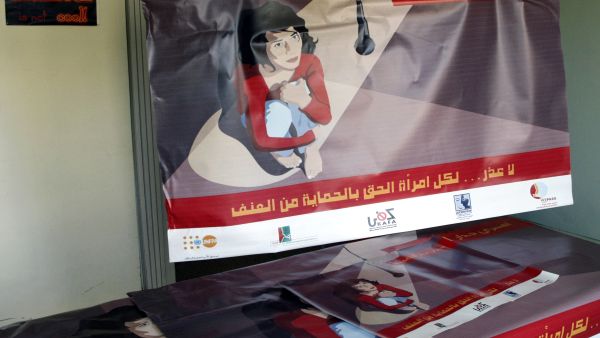 A poster that reads in Arabic, "break the wall of silence" (TOP) and "there is no excuse, every woman has the right to protection from violence" is held up at the offices of the Lebanese Council to Resist Violence Against Women (AFP/RAMZI HAIDAR)
