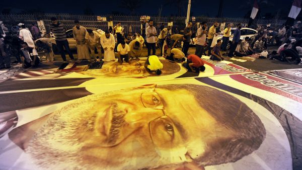 Members of the Muslim Brotherhood pray on posters of ousted Egyptian president Mohamed Mursi (AFP/FAYEZ NURELDINE)