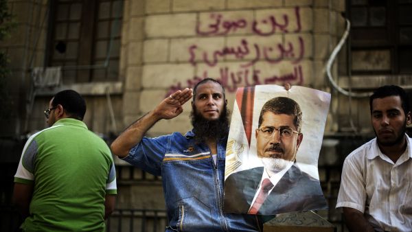 A supporter of Egypt's ousted president Mohammed Morsi holds a portrait of the former leader as he salutes during a demonstration outside the High Court in Cairo (AFP/GIANLUIGI GUERCIA)