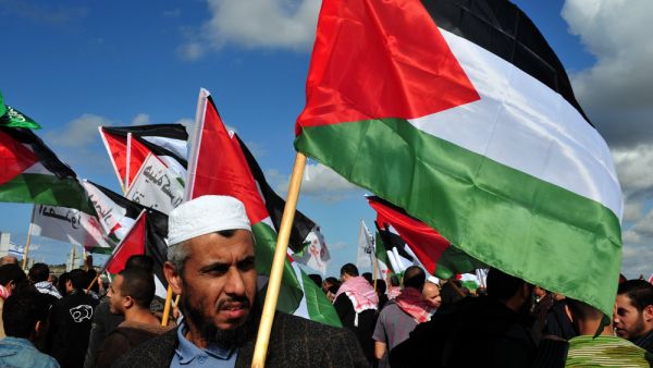 EREZ CROSSING-DECEMBER 31:Palestinian Arabs carry Palestinian flags during a protest on the Gaza-Israel border on Dec 31 2009. (Sutterstock/ChameleonsEye)