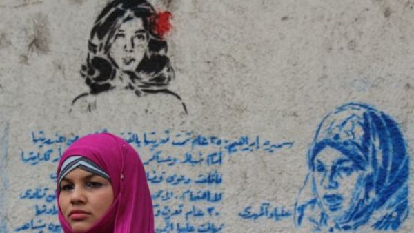 Samira Ibrahim standing next to a graffiti mural that honors her plight. (Image source: "globalpost.com")