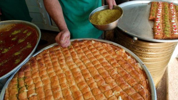 A Jordanian pastry chef puts crushed pistachio nuts on patries on the first day of the Muslim holiday of Eid al-Fitr in Amman. (Getty)