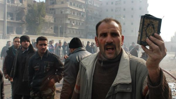A Syrian man holds up a copy of the Quran, Islam's holy book, at the scene of a reported airstrike by government forces on the central al-Fardous neighbourhood of the northern Syrian city of Aleppo on January 21, 2014. (AFP)