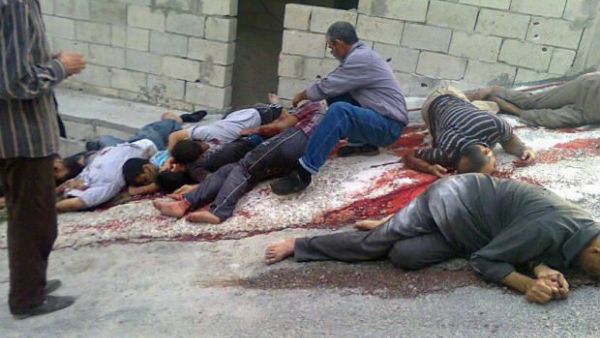 A Syrian man identifies the bodies from the massacre in the mountains outside the coastal city of Banias. (AP Image)