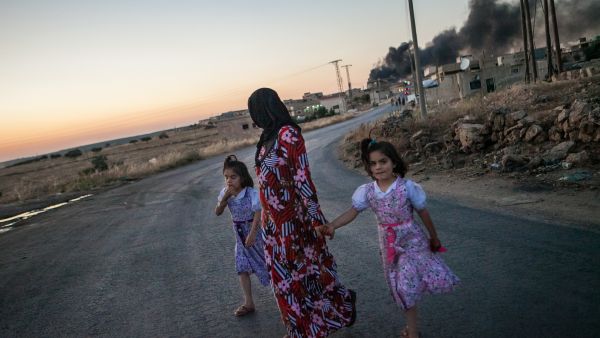 Syrian girls walk with their mother as she turns to look at smoke billowing from three shells dropped on the town of Al-Bara in the northwestern province of Idlib. (Source AFP/DANIEL LEAL-OLIVAS)