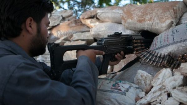  A Syrian rebel fighter points his riffle through a hole in sandbags as he holds a position in a trench, 100m far from the regime-controlled military base in Idlib province. AFP photo