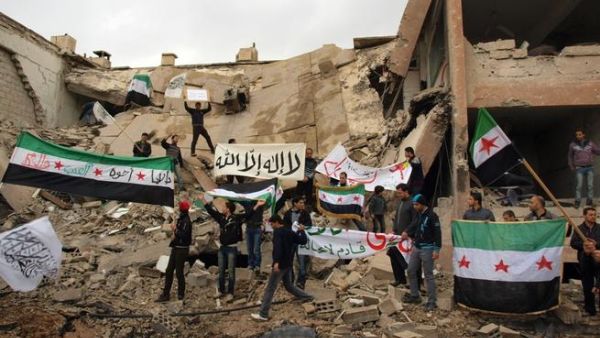 Syrians stand on the wreckage of a building, holding up placards and the Syrian pre-Baath flags during a demonstration against President Bashar Assad in Damascus last week. (AFP PHOTO/HO/SHAAM NEWS NETWORK)