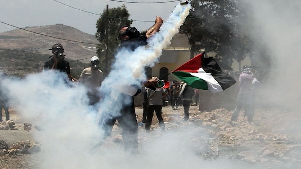 A Palestinian protester throws back a tear gas canister fired by Israeli security forces during clashes following a demonstration against the expropriation of Palestinian land by Israel in in the occupied West Bank on Friday. AFP Photo