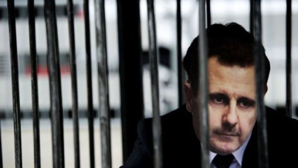 متظاهر يضع قناعا يمثل الرئيس السوري بشار الاسد ويجلس ارضا في قفص امام المحكمة الجنائية الدولية في لاهاي
