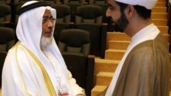 رئيس مجلس النواب البحريني خليفة الظهراني (يسار) مصافحا رجل دين شيعي في افتتاح الحوا