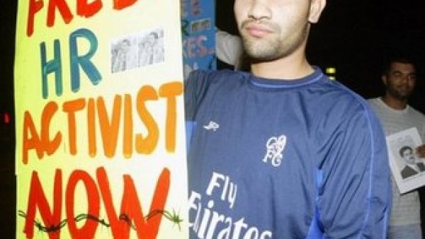 ناشط حقوقي بحريني يحمل لافتة تطالب باطلاق سراح زميل له تعتقله السلطات