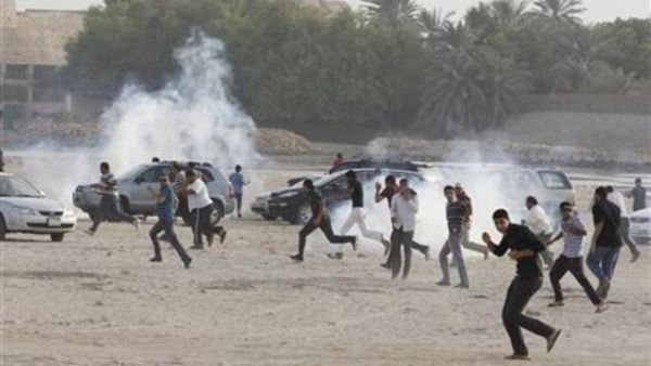 محتجون مناهضون للحكومة يفرون للاحتماء من قنابل غاز خلال مظاهرة شرقي المنامة يوم 15 يونيو حزيران 2012
