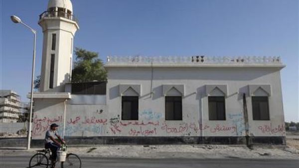 بحريني يمر بدراجة أمام مسجد في قرية دراز غربي المنامة كتبت على جدرانه الخارجية شعارات مناهضة للحكومة البحرينية