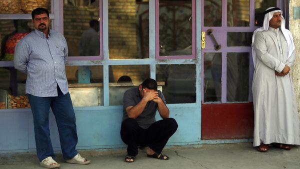 Iraqi men mourn family members on July 14, after an attack the day before (source: AFP / AHMAD AL-RUBAYE)