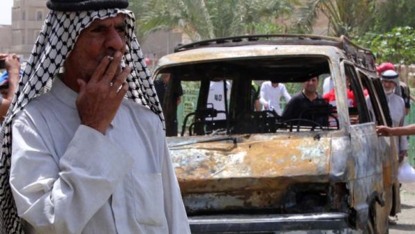 An elderly Iraqi man smokes a cigarette by the wreckage of a car bomb in Baghdad in May. (AFP/File)