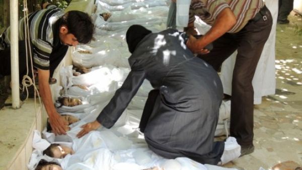 A woman mourns over a body wrapped in shrouds laid out in a line on the ground with other victims which Syrian rebels claim were killed in a toxic gas attack by pro-government forces in eastern Ghouta, on the outskirts of Damascus on August 21, 2013. (AFP/HO/Shaams News Network)