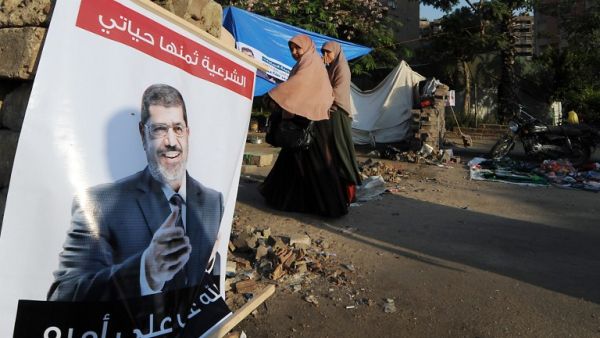 Women walk past a poster of deposed president Mohamed Morsi on July 25 in Cairo.  (AFP / FAYEZ NURELDINE)