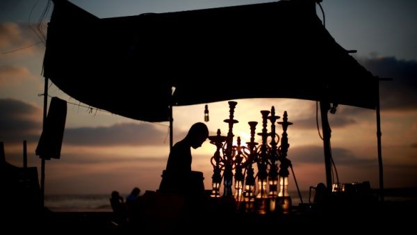 A man readies water pipes as the sun sets over the Gaza Strip during Ramadan. (AFP / Mohammed Abed)