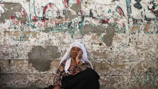 امرأة فلسطينية تجلس على الارض أمام منزلها في خان يونس بقطاع غزة
