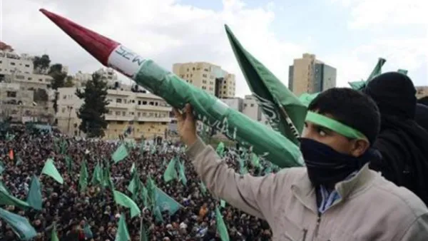 شاب فلسطيني يرفع نموذجا لصاروخ تصنعه حركة حماس خلال المسيرة في الخليل
