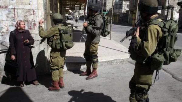 جنود اسرائيليون يوقفون سيدة فلسطينية في الجزء الفلسطيني من مدينة الخليل
