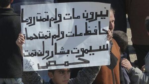 صبي يرفع لافتة تندد بالاسد في بلدة الحولة قرب حمص 
