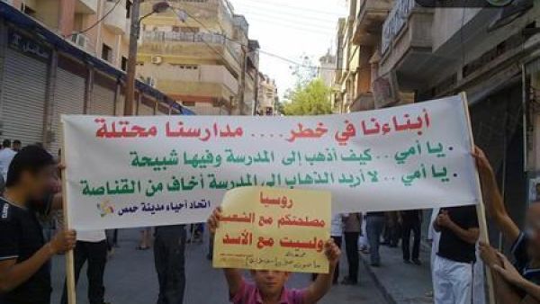 طلاب سوريون يرفعون لافتة أثناء مظاهرة مناهضة لنظام الأسد في حمص ي