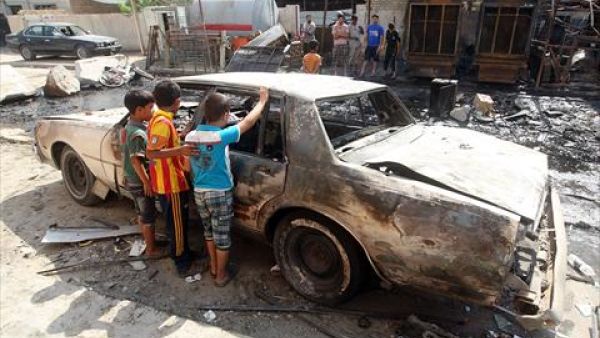 Iraqi children inspect a burnt-out car at the site of a car bomb attack that exploded the previous day in a commercial street of Baghdad's eastern neighbourhood of Mashtal on Monday. On Tuesday, a fresh wave of violence across the country killed at least 24 people. (AFP)