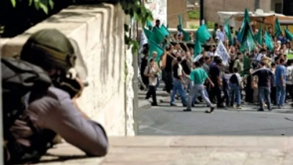 شرطي اسرائيلي يصوب بندقيته باتجاه متظاهرين من عرب 48 خلال احداث عام 2000