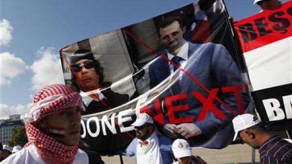 معارض سوري يحمل صورة للقذافي والاسد خلال احتجاج بوسط اسطنبول
