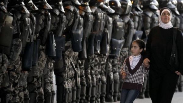 امراة وطفلة تمران من امام طابور لقوات الامن في الاردن