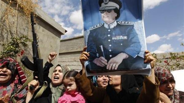 صورة أرشيفية لنساء وأطفال من من الموالين للزعيم الليبي السابق في بني وليد يرفعون أسلحة وصورة للقذافي