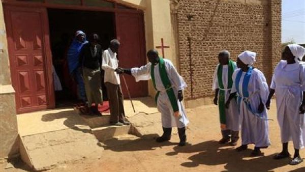 قس يساعد عجوزا بعد حضوره الصلاة في كنيسة على مشارف الخرطوم
