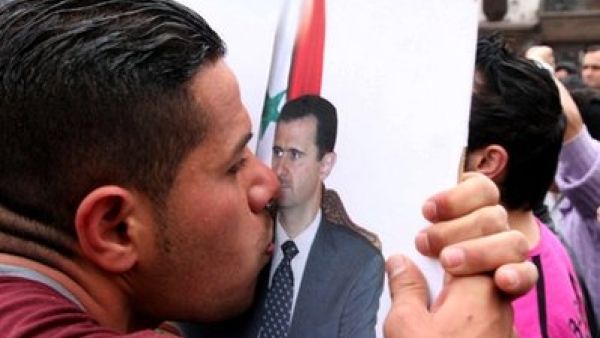 متظاهر من الموالين للاسد يقبل صورته في دمشق