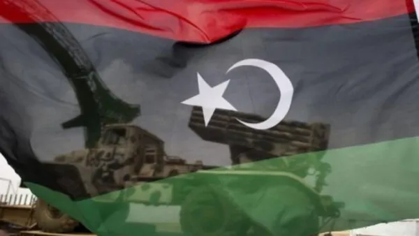 علم للثوار وخلفه عربة محملة بقاذفة صواريخ في اجدابيا