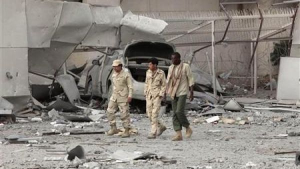  مسؤولون ليبيون يسيرون يوم الاثنين أمام مبنى في مجمع القذافي في باب العزيزية لحقت به أضرار جسيمة جراء هجوم حلف الأطلسي
