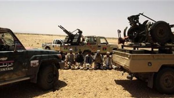 مقاتلون من المعارضة الليبية يصلون بين سياراتهم على الجبهة في بلدة بير غنام 
