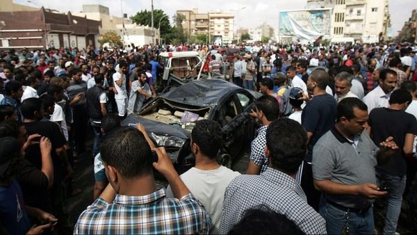 Bystanders and residents gather next to the wreckage of a car at the site of a car bomb that exploded in the parking lot of a Benghazi hospital in Libya on Monday. (AFP Photo)