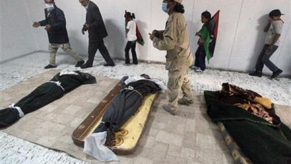 مواطنون ليبيون يلقون نظرة على جثامين معمر القذافي وابنه المعتصم بالله وقائد قواته ابو بكر يونس في مصراتة 
