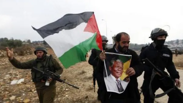 فلسطيني يحمل صورة لمانديلا خلال احتجاج ضد المستوطنات اليهودية في النبي صالح بالضفة الغربية
