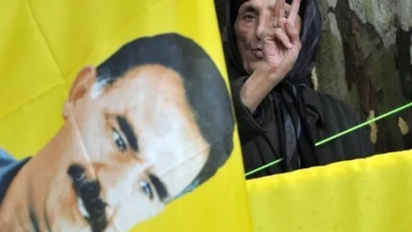 مناصرة لعبد الله اوجلان زعيم حزب العمال الكردستاني تقف خلف صورته وترفع يدها باشارة النصر