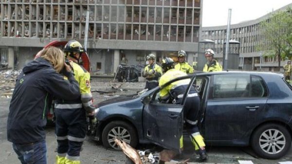 رجل يلتقط صورا فيما رجال الاطفاء يعملون في موقع الانفجار امام مكاتب رئيس الوزراء النروجي في اوسلو
