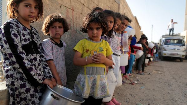 Syrian children wait in line to collect a free “Iftar” meal in the northern city of Raqqa during the Muslim holy month of Ramadan on July 14, 2013 (Source: AFP/MEZAR MATAR)