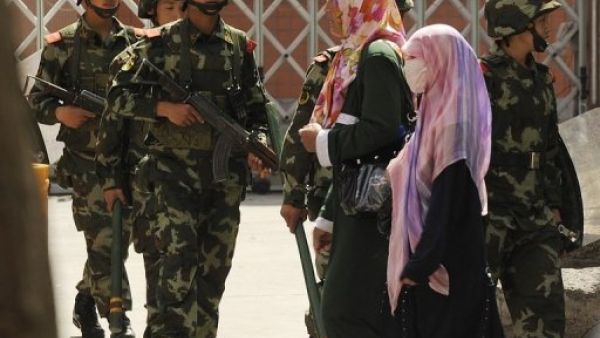 نساء يعبرن من امام جنود صينيين في شينغيانغ