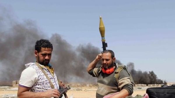 اعمدة دخان ترتفع خلف مقاتلين من الثوار في موقع يبعد نحو 130 كلم شرق سرت