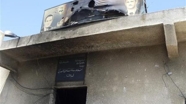 لافتة محترقة عليها صورة لبشار الأسد ووالده الراحل حافظ الأسد فوق مدخل لحزب البعث تعرض للاحراق في بلدة قرب درعا يوم السبت
