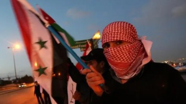 متظاهر سوري يحمل العلم الوطني خلال تظاهرة امام السفارة السورية في العاصمة الاردنية