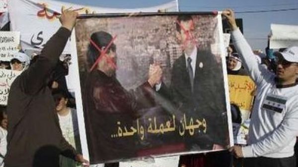 متظاهرون سوريون في العاصمة الاردنية يحملون لافتة تندد بالاسد وتشبهه بالقذافي